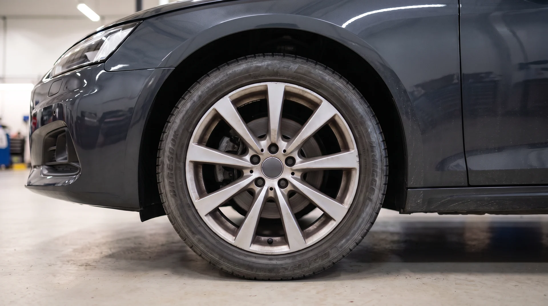 A wheel before detailing, brake dust dulling the spokes and the tire sidewall faded grey